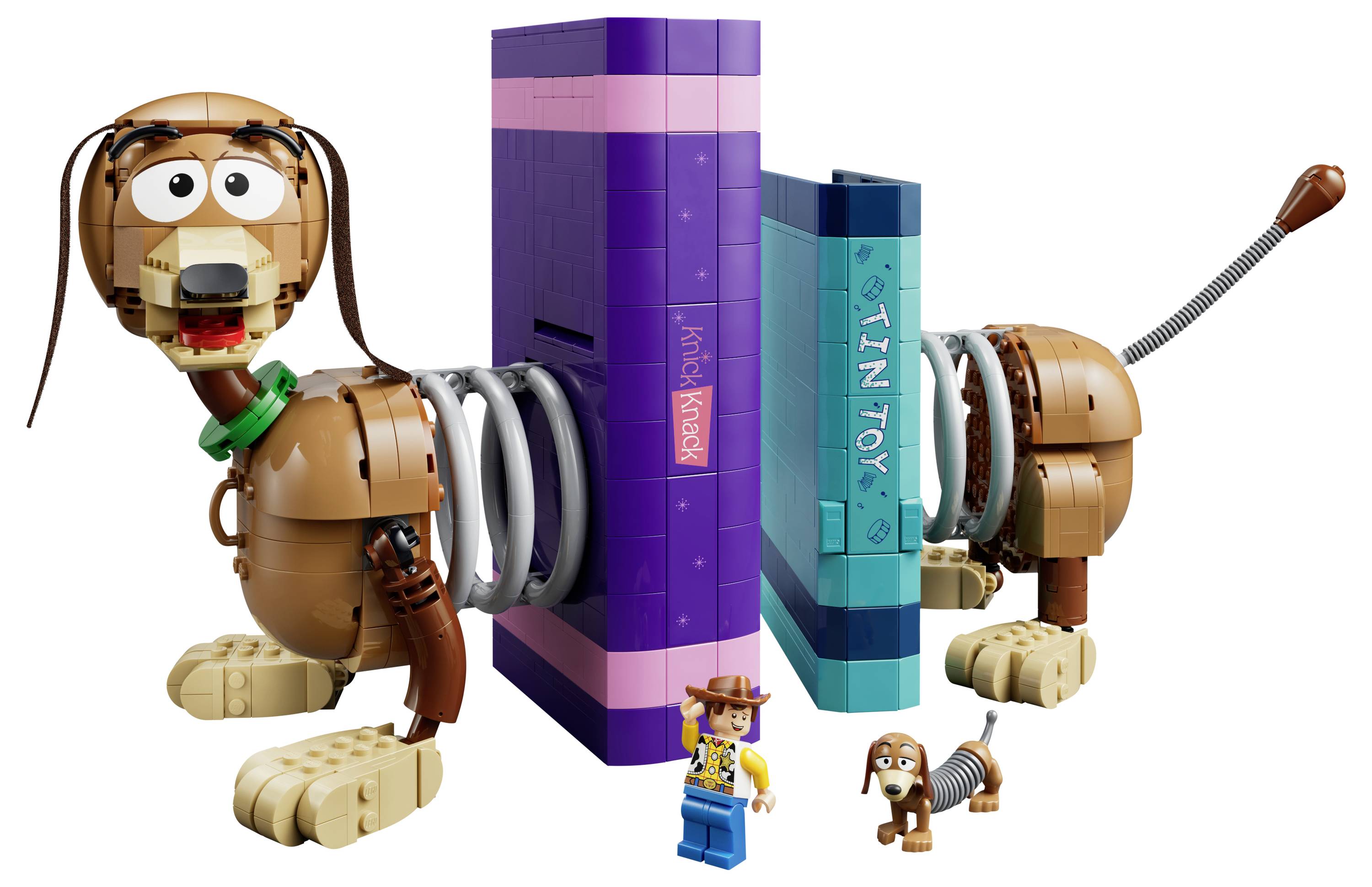 Spielzeughundfiguren befestigen sich an großen lila und blaugrünen batterieähnlichen Blöcken, was auf ein batteriebetriebenes Hundesspielzeugset hindeutet; ein kleiner LEGO-ähnlicher Cowboy und Hund stehen davor.