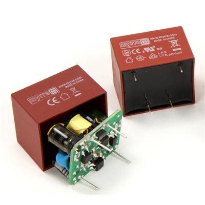 Two red power supply modules; one shows internal capacitors and pins, the other is closed. Both have technical symbols and labels.