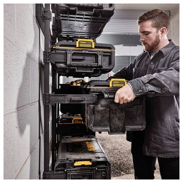 Eine Person organisiert robuste schwarz-gelbe Werkzeugkästen auf einem an der Wand befestigten Regal in einer Garage und betont dabei effiziente Lagerhaltung.