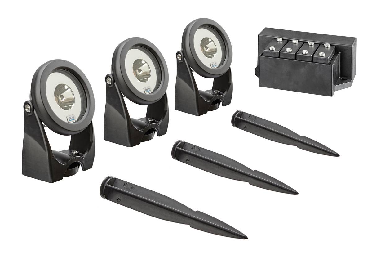 Three black spotlight-like devices with three pointed ground stakes and a battery pack, shown as a lighting set on a white background.