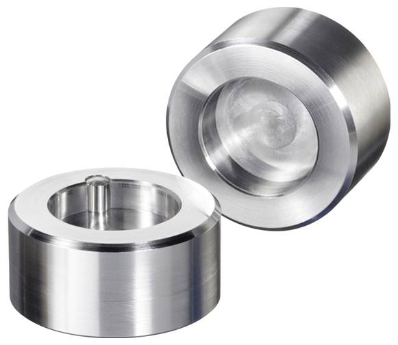 Zwei metallische zylindrische Gewichte mit vertieften Mittelpunkten, eines aufrecht und das andere geneigt, die polierte Oberflächen zur Schau stellen.