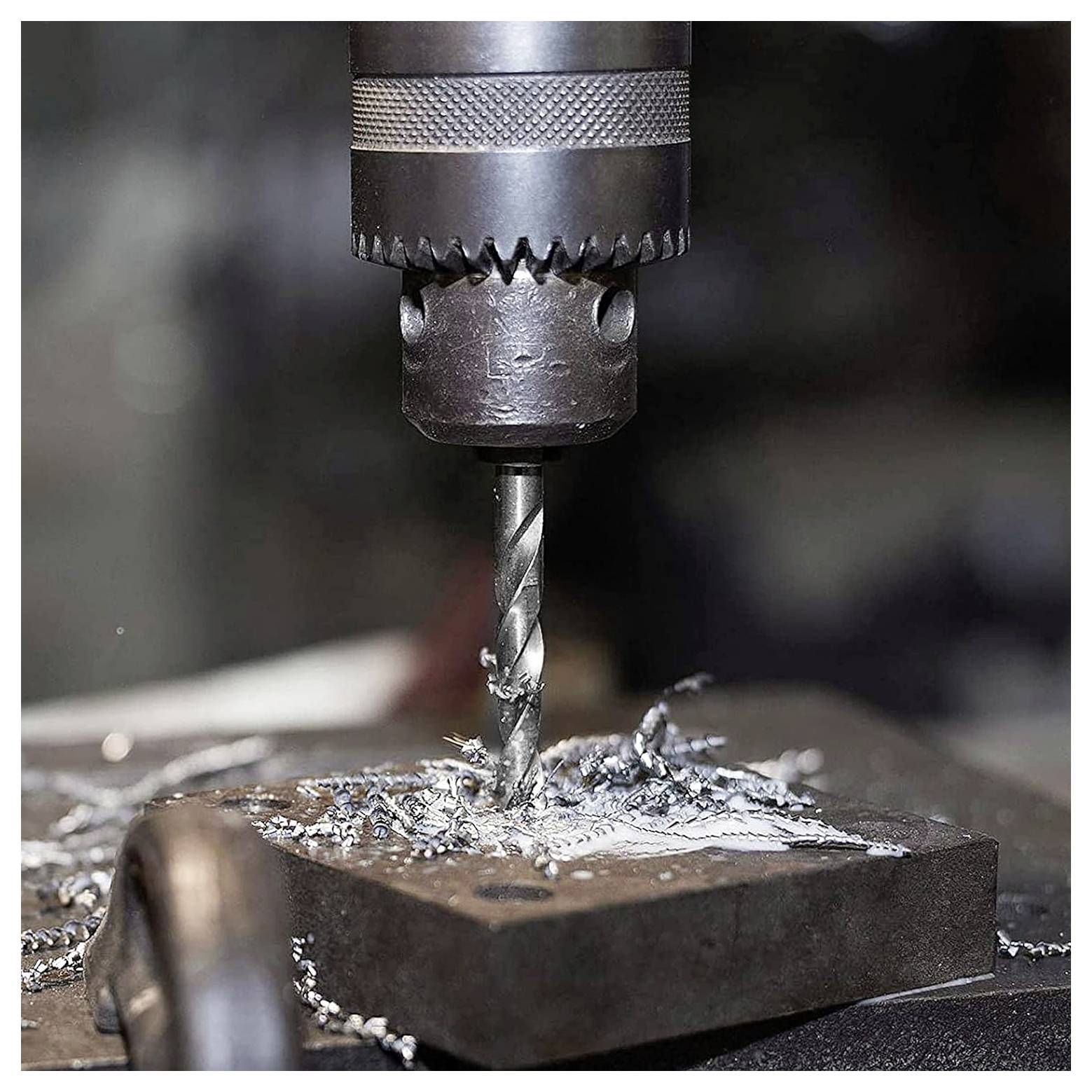 Eine in Betrieb befindliche Metallbohrmaschine mit einem Bohrmeißel, der in einen Metallblock eindringt, umgeben von Metallspänen auf der Oberfläche.