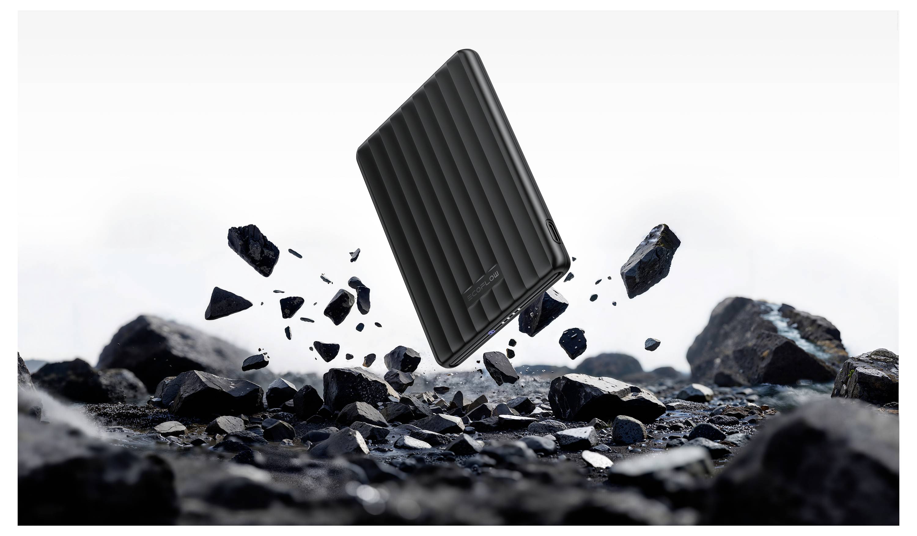Ein robuster tragbarer Festplattenspeicher schwebt über felsigem Gelände, umgeben von fliegenden Trümmern, was Langlebigkeit und Stoßfestigkeit andeutet.