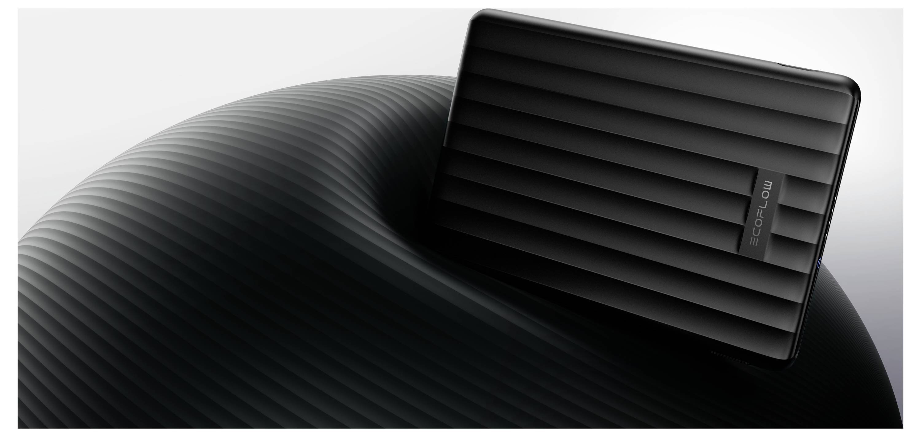 Eine schwarze, gestreifte Festplatte ruht auf einer gewölbten, gerippten Oberfläche vor einem hellen Hintergrund und zeigt ihr schlankes, modernes Design.