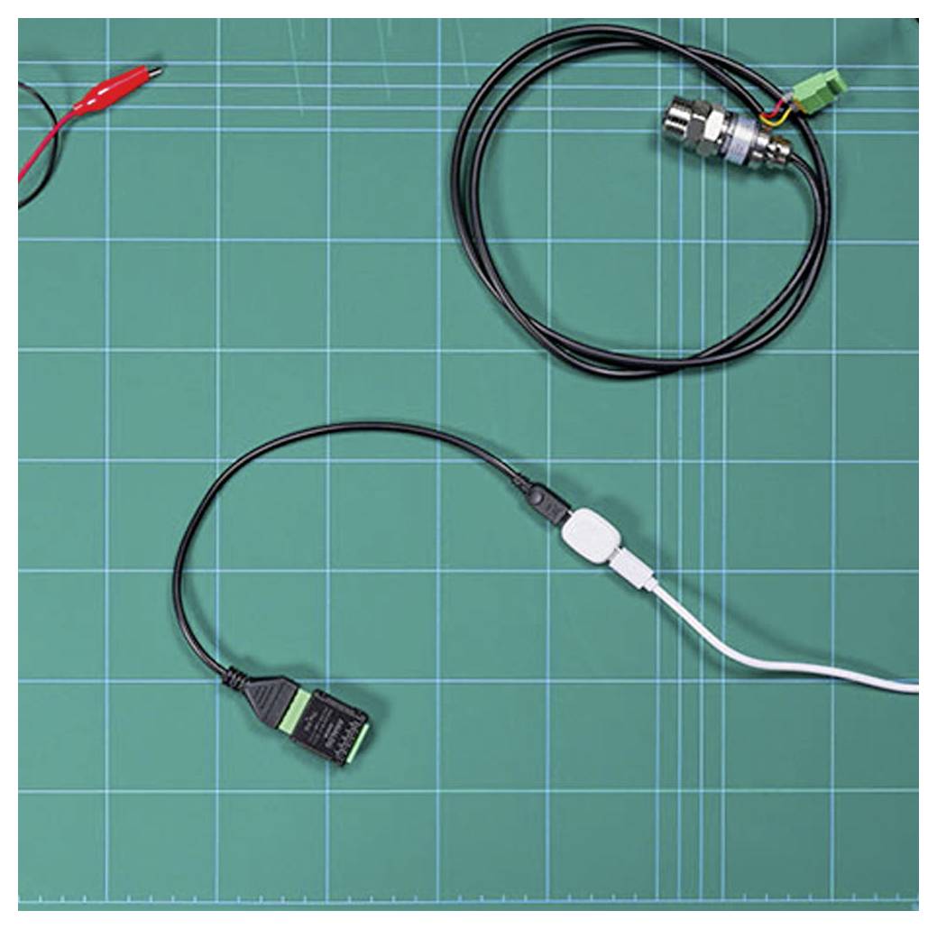 Eine grüne Gittermatte mit Kabeln, Steckern und einem darauf platzierten Sensor. Die Matte wird zur Organisation und Montage von elektronischen Komponenten verwendet.