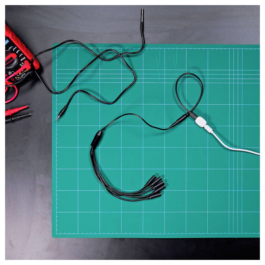 Ein Multimeter und Messleitungen liegen auf einer grünen Schneidematte, bereit für elektrische Tests.