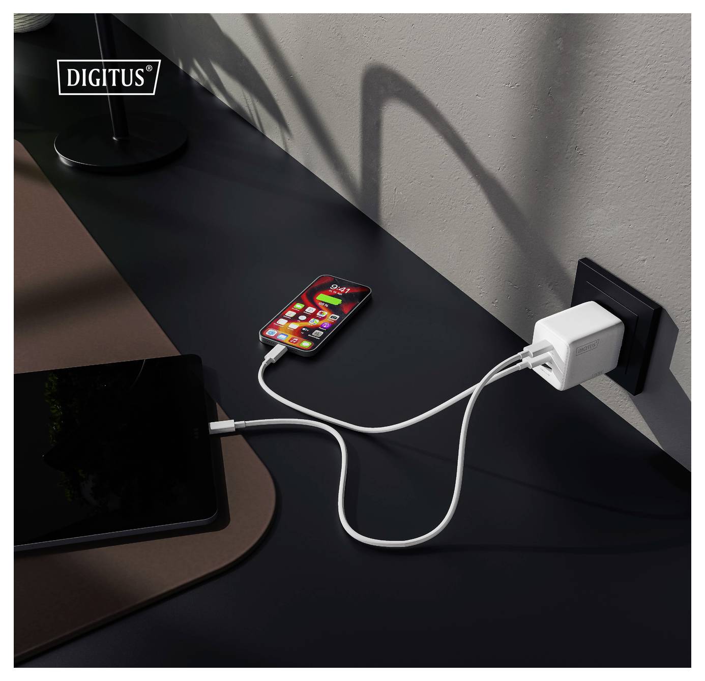 Ein Smartphone und Tablet laden auf einem Schreibtisch mit einem Doppel-Port-Wandladegerät.