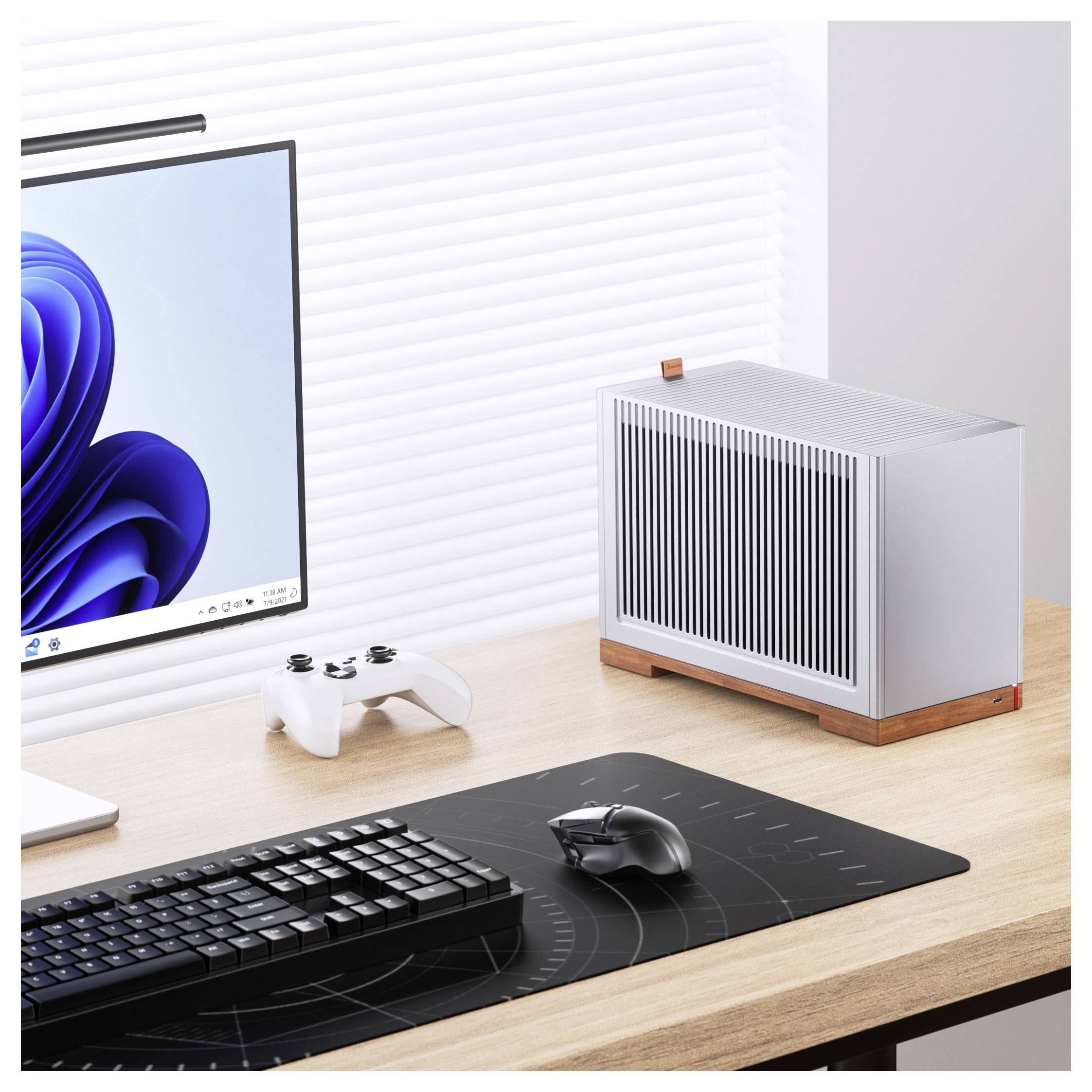 Ein modernes Schreibtischset mit einem schlanken Computermonitor, einer kabellosen Tastatur und Maus auf einer Matte und einem minimalistischen PC-Gehäuse auf einem Holzschreibtisch.