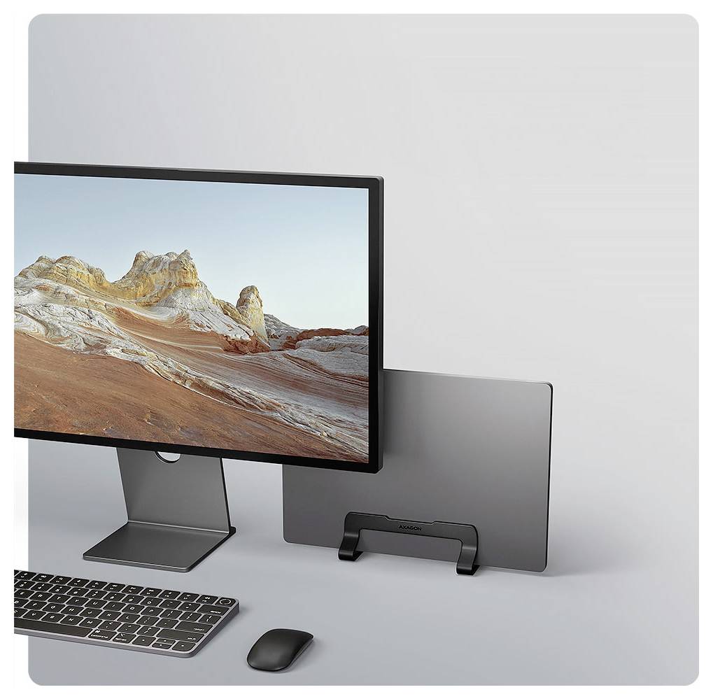 Ein Computermonitor zeigt ein Landschaftsbild an, mit einer Tastatur und einer Maus davor, und ein Laptop auf einem Ständer zur Seite.