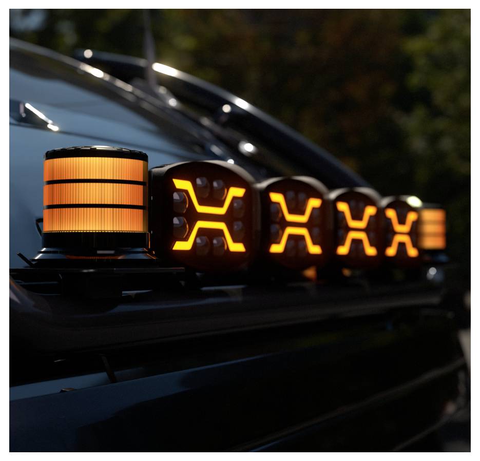 Nahaufnahme einer Fahrzeugdachleiste mit leuchtenden orangefarbenen Warnleuchten und beleuchteten X-förmigen Signalen, aufgenommen in der Dämmerung.