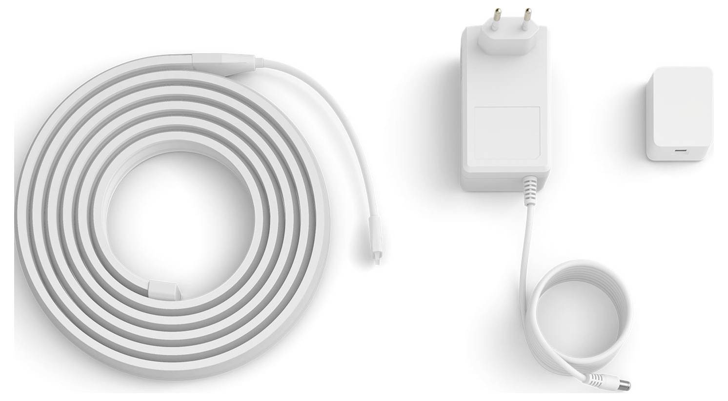 Aufgerolltes Ladekabel, Wandadapter mit zweipoliger Steckdose und ein kleines rechteckiges Gerät. Auf weißem Hintergrund angeordnet.