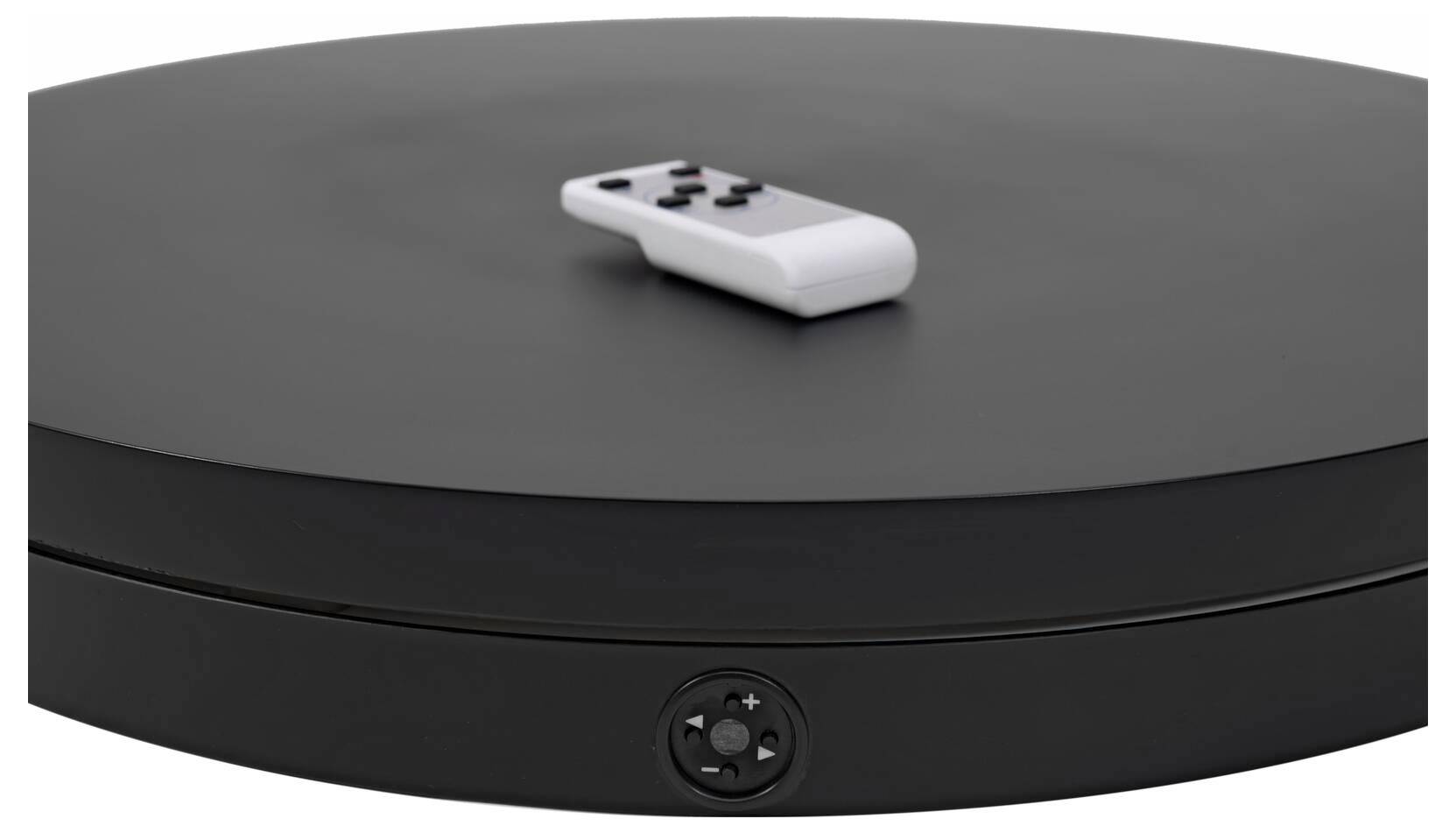 Ein schwarzer Plattenspieler mit einer Fernbedienung oben drauf, mit Steuertasten an der vorderen Kante.