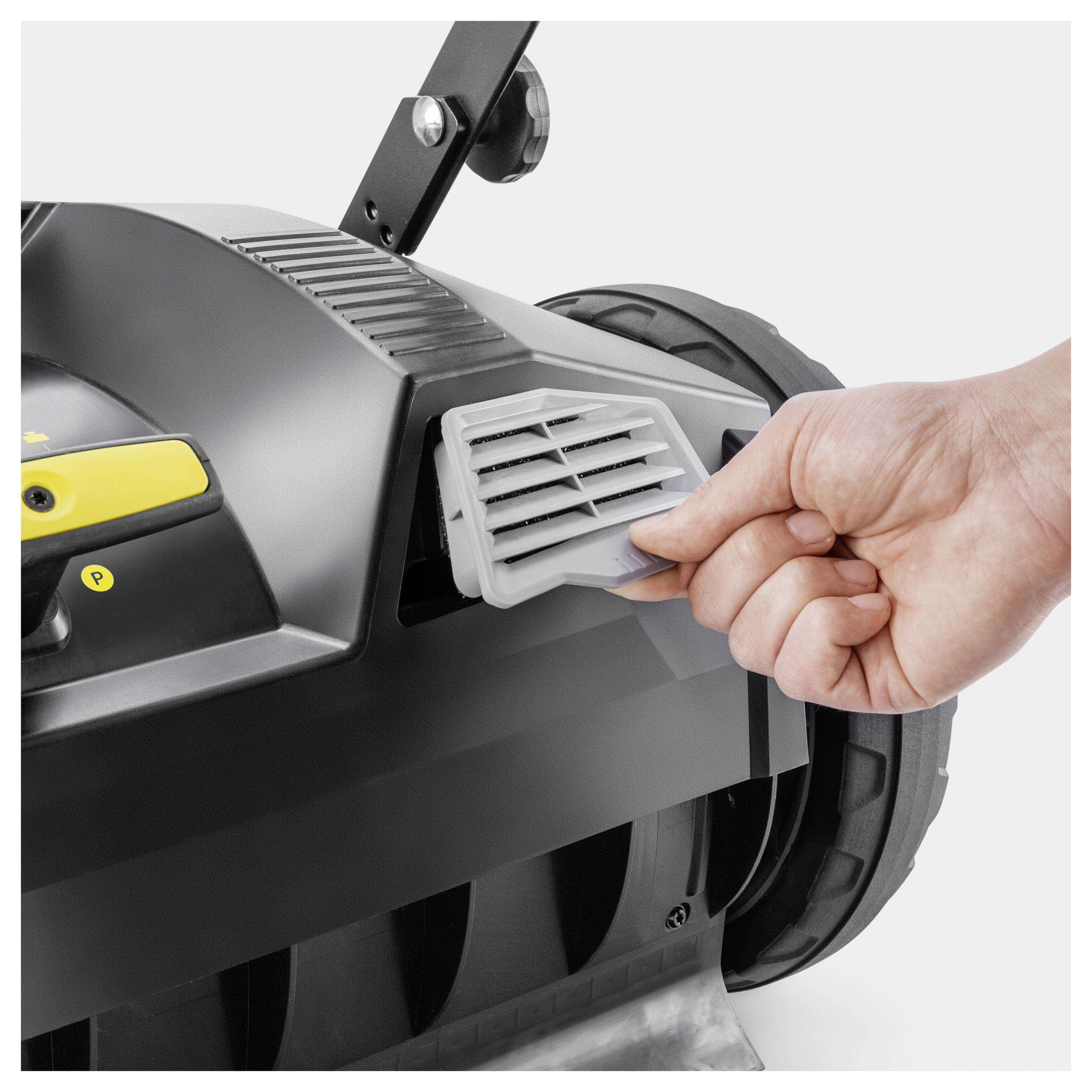 Eine Hand stellt eine Lüftungsöffnung an einem Gerät ein, möglicherweise an einem Rasenmäher, wobei der Fokus auf Wartung oder Funktionalität liegt.