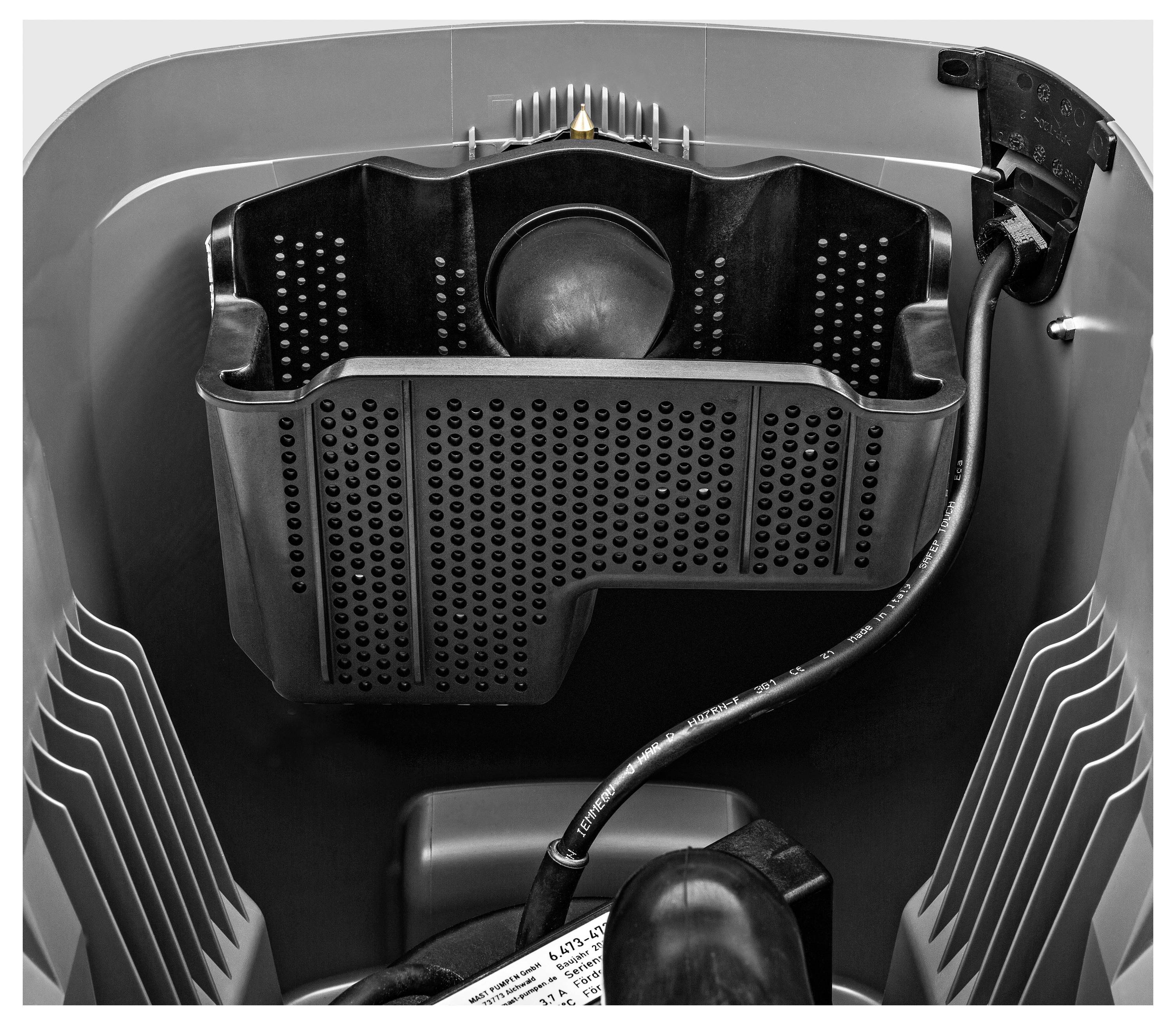 Eine Nahaufnahme einer Waschmaschinentrommel mit deutlichem schwarzem Ablaufteil und Schlauch, die das innere Design und die Textur hervorhebt.