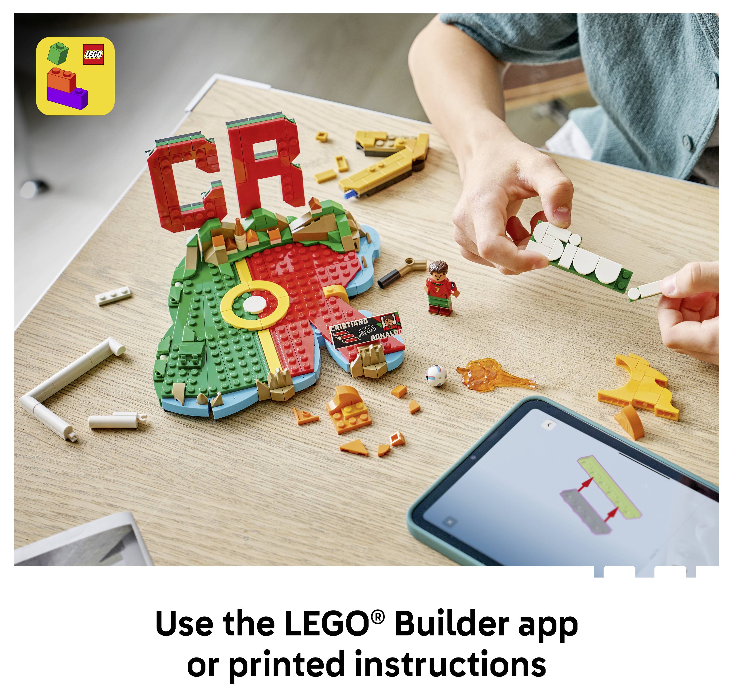 Hände bauen ein LEGO-Mosaik und lose Steine auf einem Tisch, mit Text, der besagt „Verwenden Sie die LEGO® Builder-App oder gedruckte Anleitung
