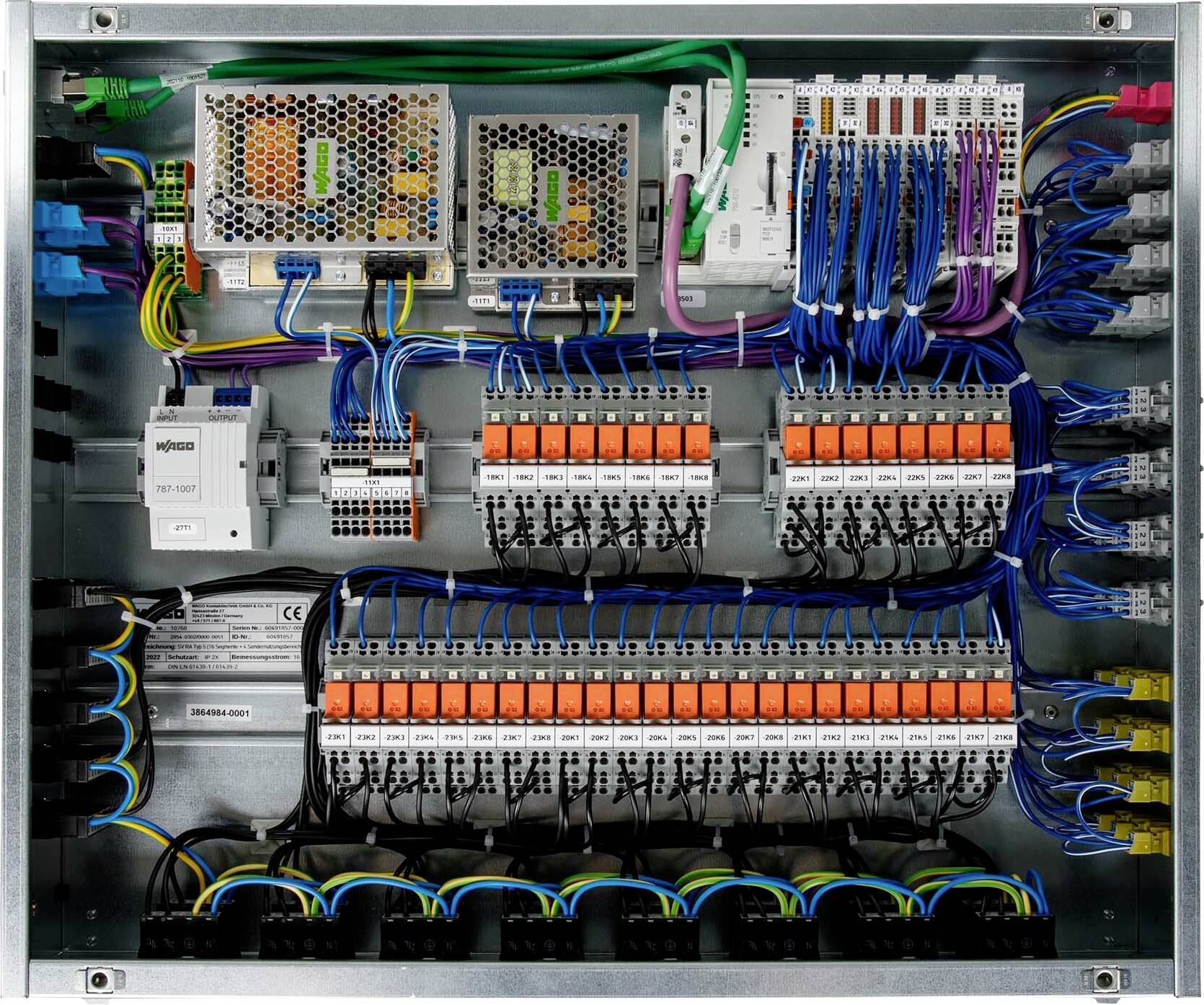 Ein Elektroschaltschrank mit verschiedenfarbigen Drähten, die an Klemmenleisten, Leistungsschaltern und speicherprogrammierbaren Steuerungskomponenten angeschlossen sind, was auf eine komplexe Verdrahtungsanlage hinweist.