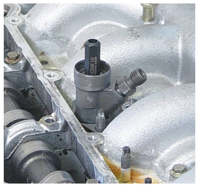 Eine Motorkomponente mit sichtbarem Ventil und Bolzen, die metallisch und mechanisch wirkt und wahrscheinlich Teil eines Verbrennungsmotorsystems ist.