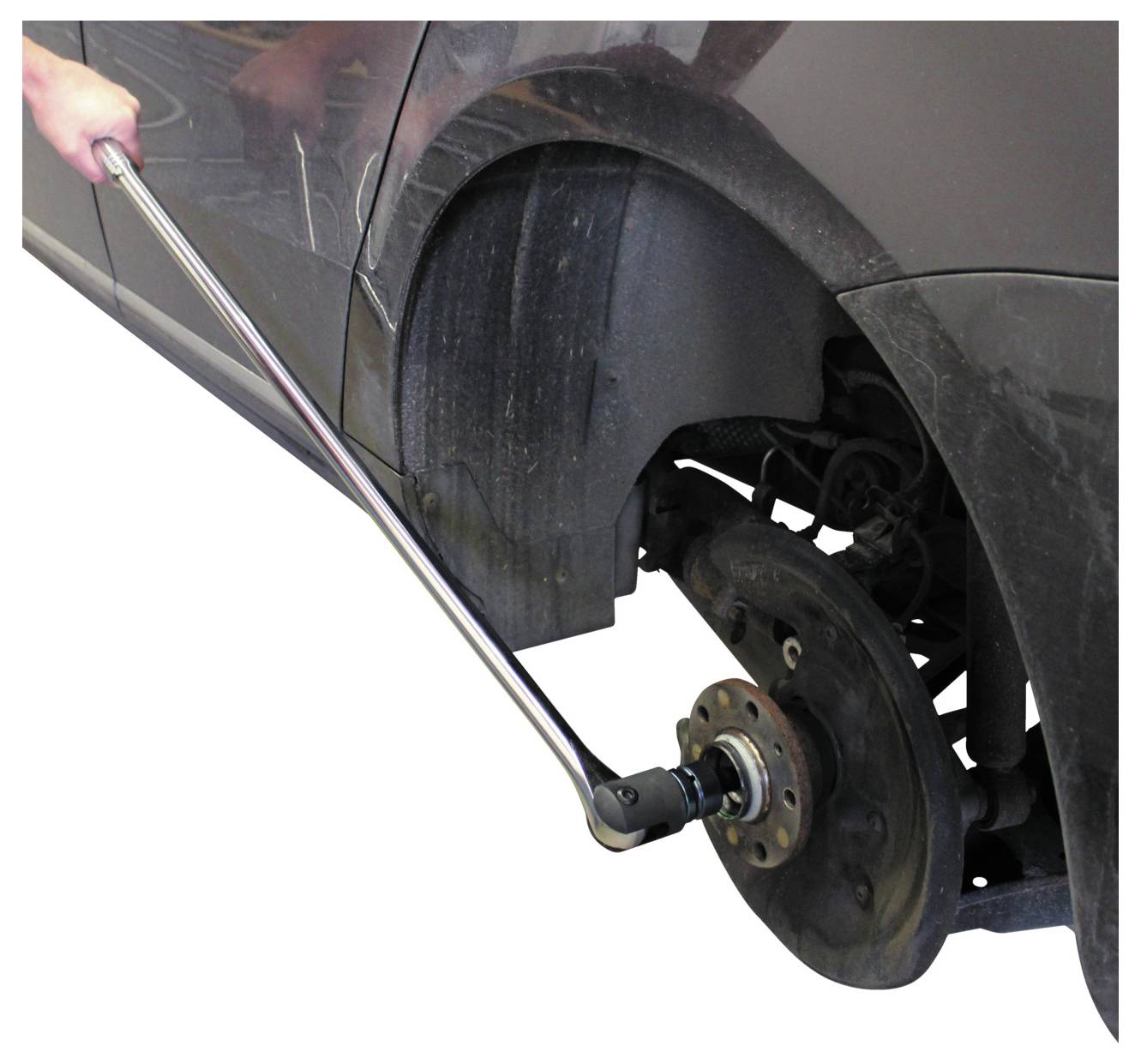 Eine Person verwendet einen Drehmomentschlüssel, um einen Bolzen an der Radnabe eines Autos mit entferntem Rad festzuziehen.