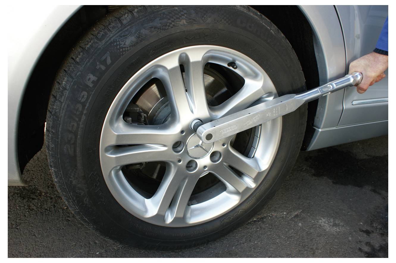 Eine Person verwendet einen Drehmomentschlüssel, um eine Radmutter an einem Autrad festzuziehen, um sicherzustellen, dass das richtige Drehmoment für die Sicherheit aufgebracht wird.