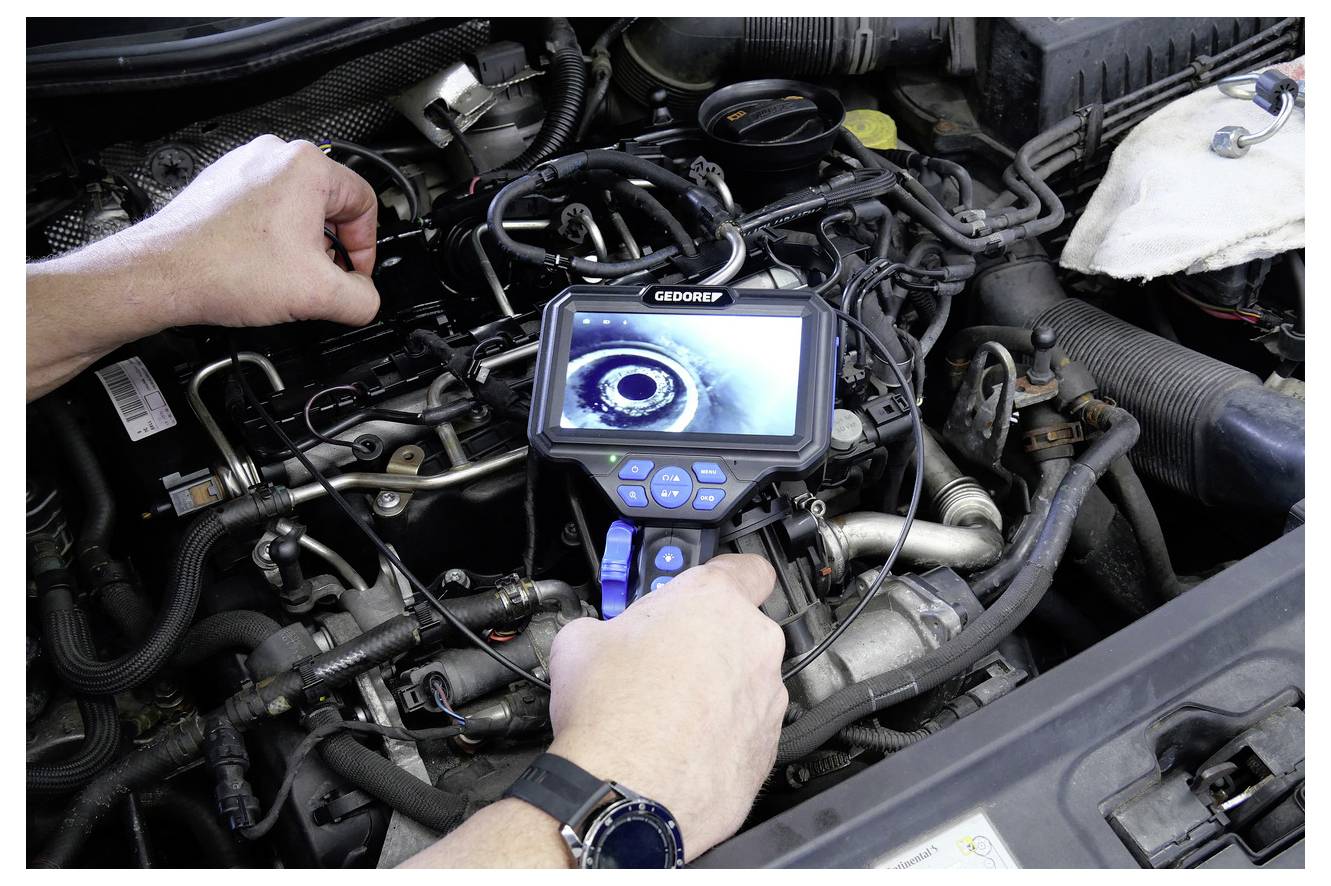 Eine Person nutzt eine digitale Inspektionskamera, um komplizierte Komponenten eines Automotors zu untersuchen, wobei Reparatur- und Diagnosearbeiten hervorgehoben werden.