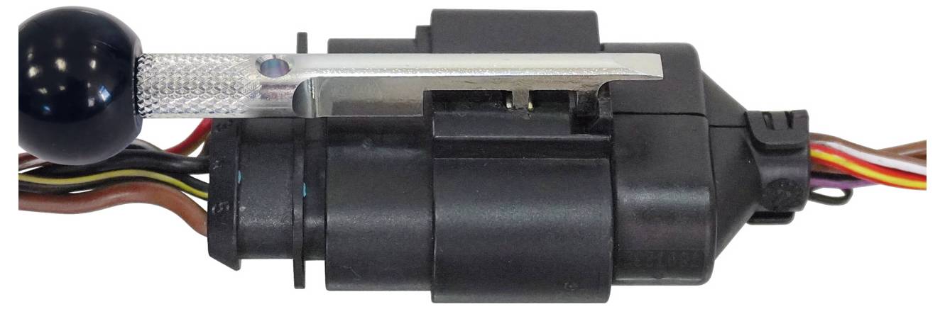 Eine Nahaufnahme eines Automobilkomponents mit mehreren angeschlossenen Drähten, das einen Hebel an der Seite aufweist.