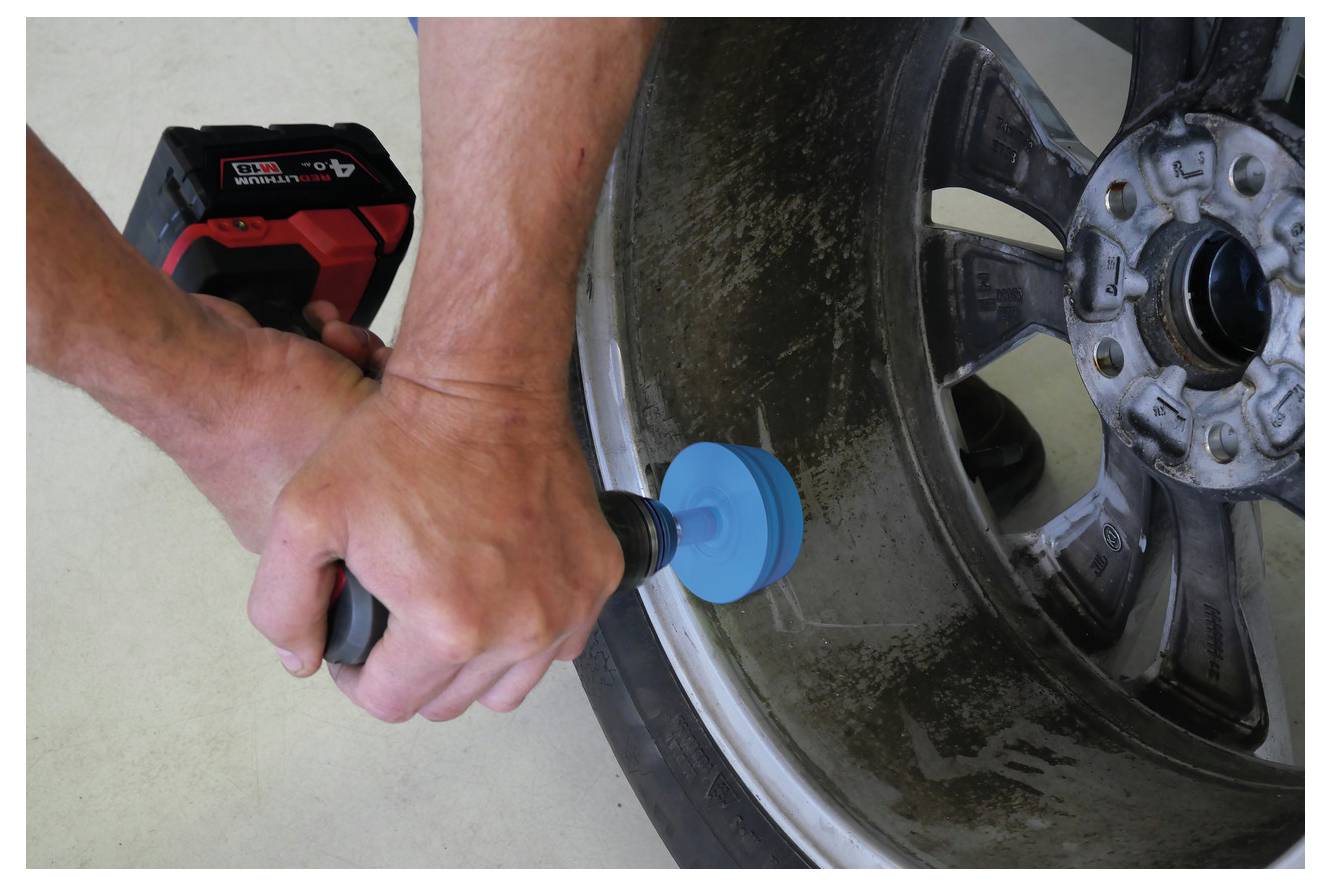 Eine Nahaufnahme eines Schraubenschlüssels, der eine Schraube auf einer rostigen Metalloberfläche anzieht, zeigt industrielle Reparaturarbeiten.