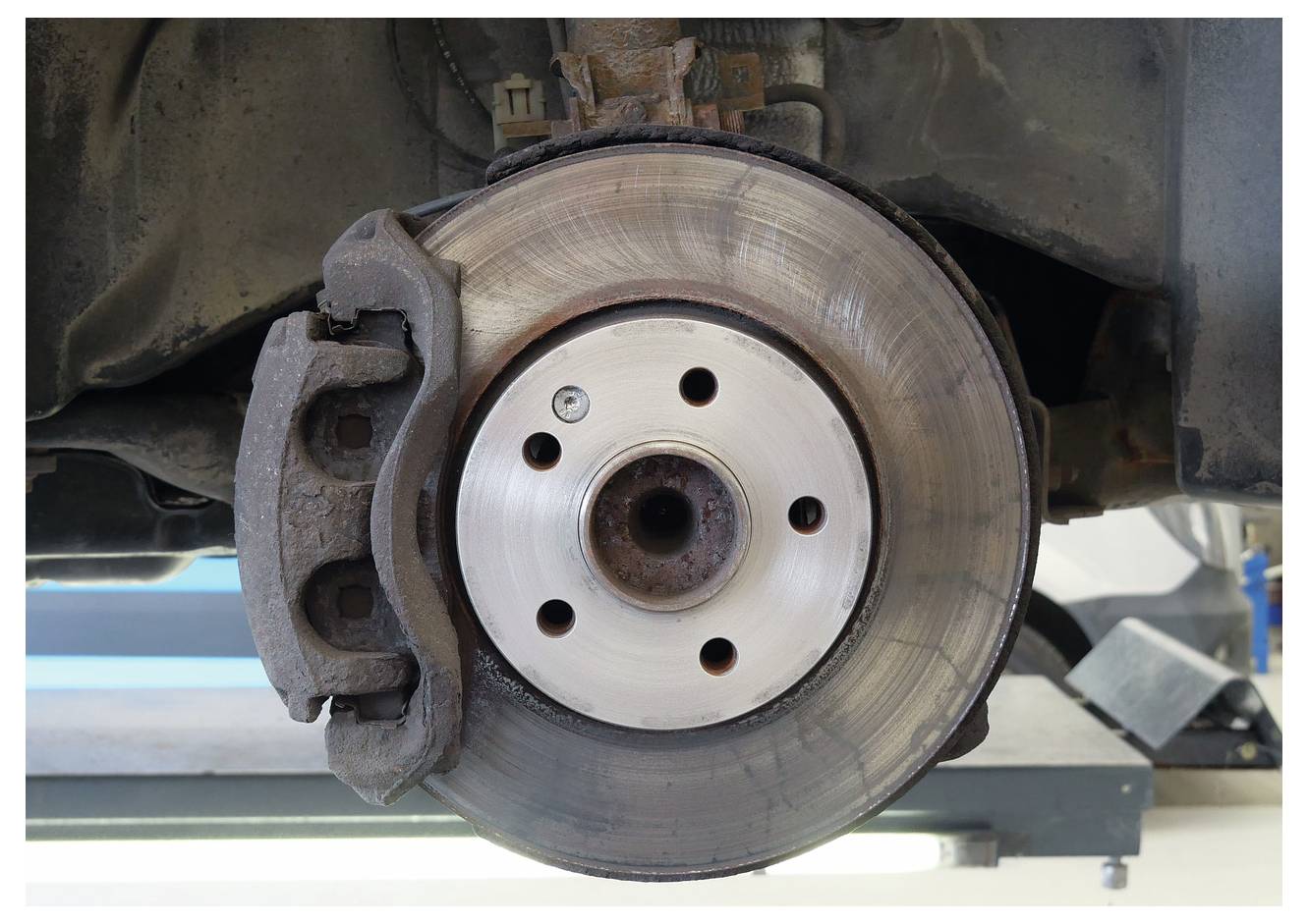 Eine Bremsscheibe und ein Bremssattel eines Autos werden in Nahaufnahme gezeigt und offenbaren Details der Oberfläche der Scheibe und die Position des Bremssattels zur Wartung.