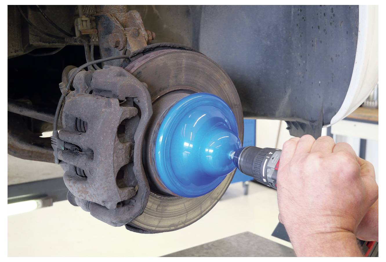 Ein Werkzeug mit einer Buchse wird an einer rostige Radnabe eines Autos befestigt und zeigt, wie man ein Radlager entfernt oder einbaut.