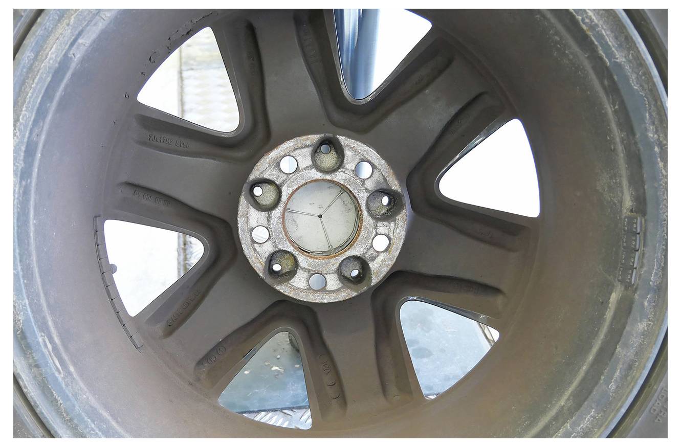 Eine Metallklemme mit einem schwarzen Schraubengriff sichert ein transparentes Rohr. Die Klemme ist mit „KLC