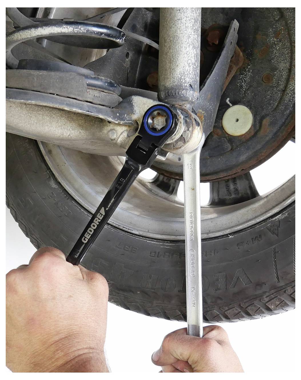 Eine Person misst den Durchmesser eines Autorads mit einer Schieblehre und zeigt, wie man die Reifengröße an einem blauen Fahrzeug genau bestimmt.