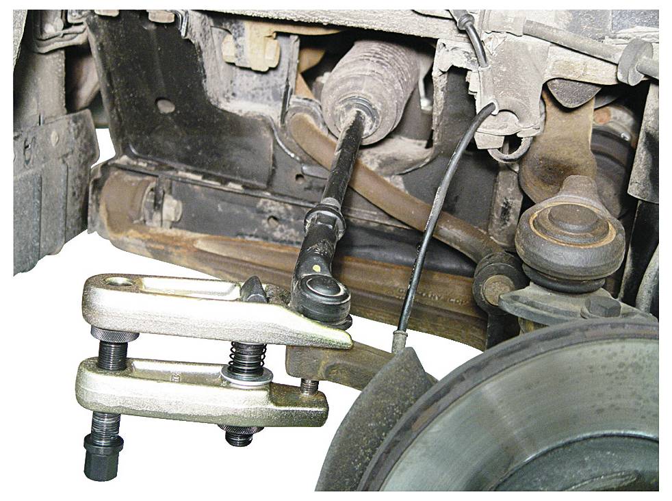 Das Bild zeigt einen Kugelgelenk-Abzieher in Gebrauch, der ein Kugelgelenk aus einer Fahrzeugsuspensionsbaugruppe entfernt und hebt eine Autoreparatur hervor.