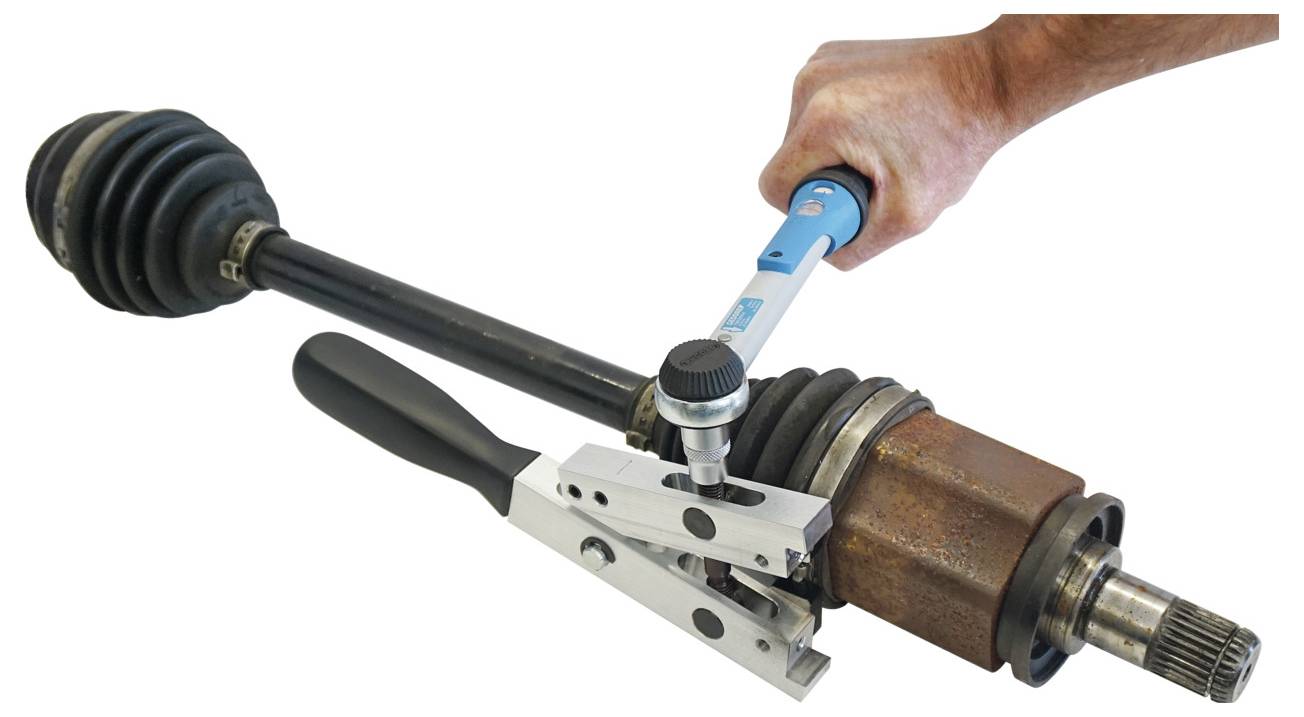 Eine Person verwendet einen blauen Drehmomentschlüssel, um ein Metallgerät auf einer Fahrzeugachse festzuziehen, wobei ein Teil der Montage oder Wartung demonstriert wird.