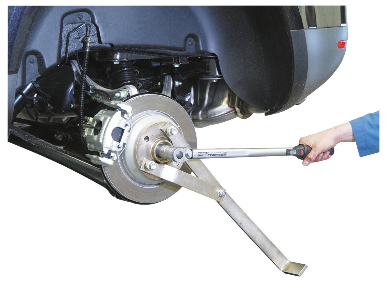 Die Radausrichtung eines Fahrzeugs wird mit einem Drehmomentschlüssel eingestellt. Die Hand einer Person hält den Schlüssel und zielt auf ein Schlüsselbauteil in der Nähe der Bremsscheibe.