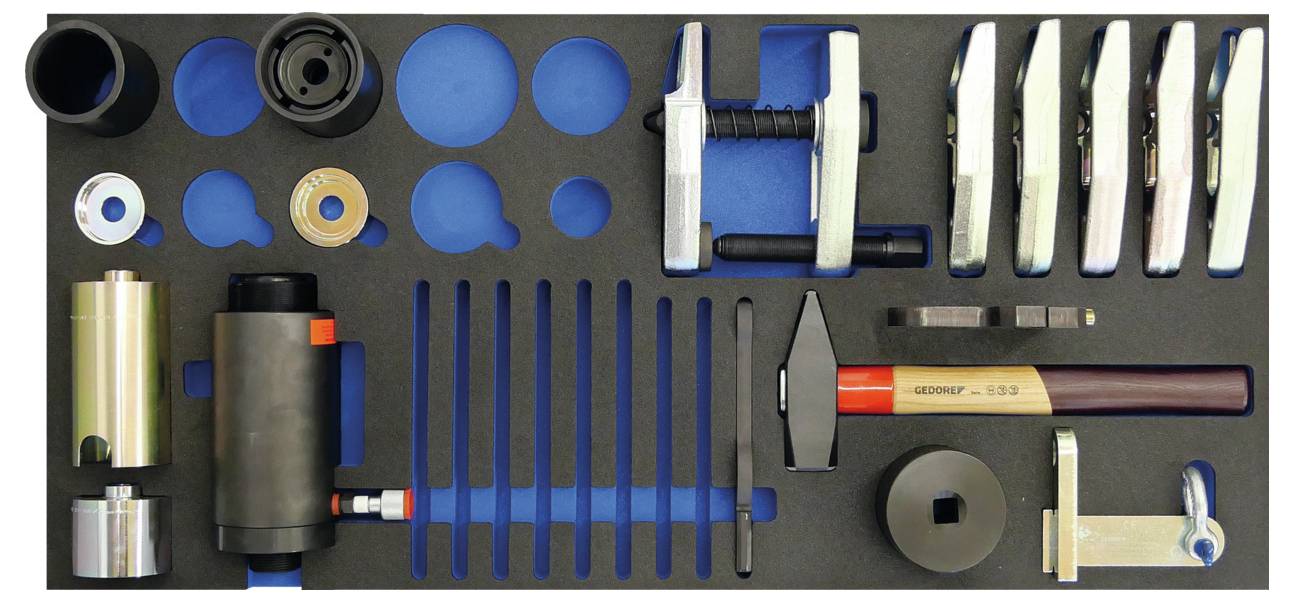 Ein Schaumstoff-Werkzeugorganizer mit verschiedenen Werkzeugen wie einem Holzhammer, Metallzwingen, einem Schraubenschlüssel und kreisrunden Ringen.