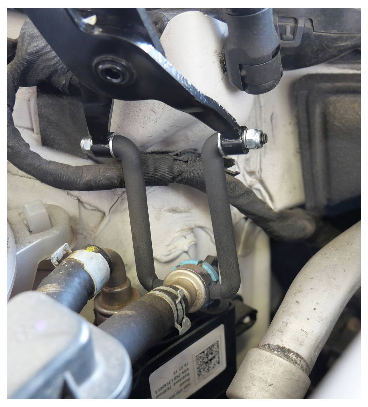 Eine Engine-Komponente mit einer Metallhalterung und Schläuchen, die an einer größeren mechanischen Baugruppe befestigt ist und einen Teil eines Kraftfahrzeugsystems anzeigt.