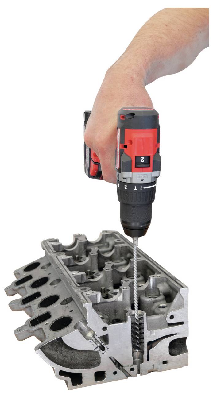 Eine Hand, die einen roten Bohrer zur Reparatur eines Motorzylinderkopfs verwendet, wobei der Bohrer in eines der Zylinderlöcher eingeführt ist.