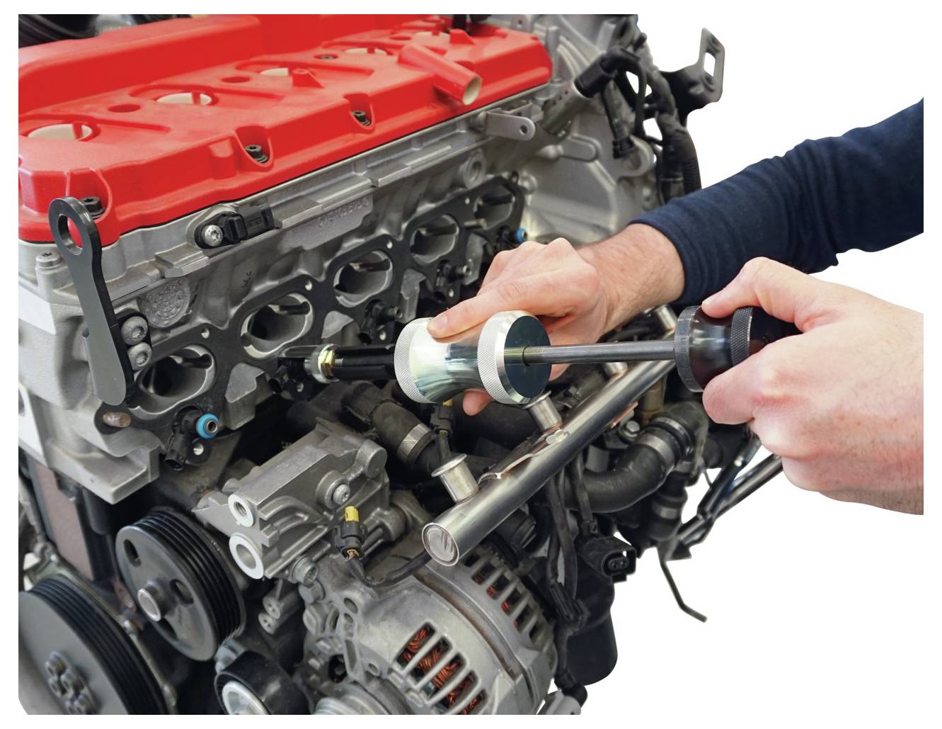 Mechaniker verwendet Werkzeug an offenem Automotor mit roter Abdeckung und sichtbaren Kolben, um Wartungs- oder Reparaturarbeiten durchzuführen.