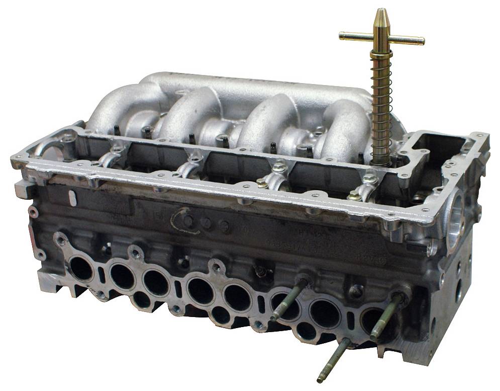 Ein Zylinderkopf eines Motors mit sichtbarem Ansaugkrümmer, Brennräumen und Zündkerzenlöchern, die mechanische Komponenten zeigen.