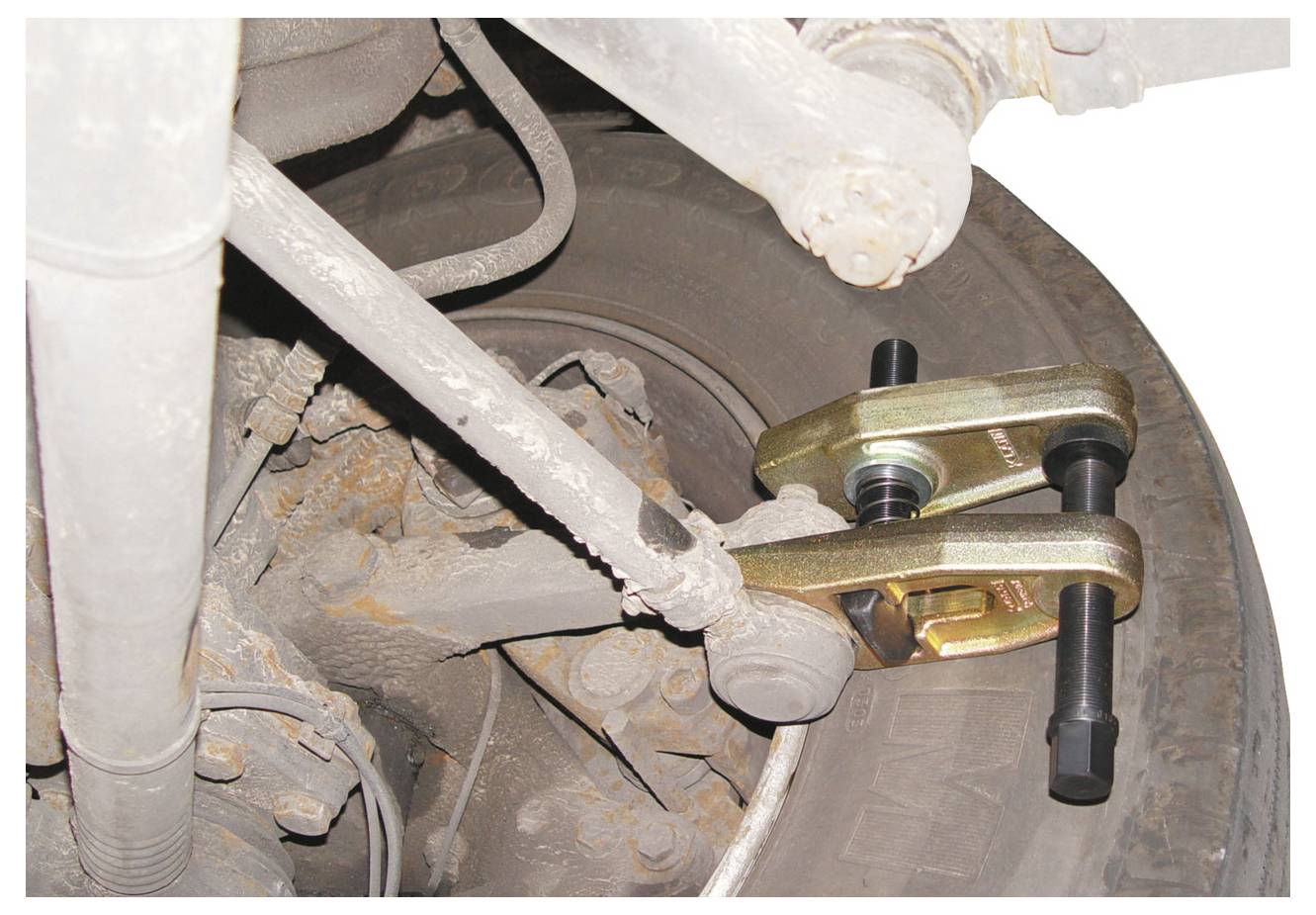 Ein Kugelgelenkabzieher ist an einem Aufhängungssystem eines Fahrzeugs angebracht und veranschaulicht die Anwendung des Werkzeugs zum Entfernen von Kugelgelenken.