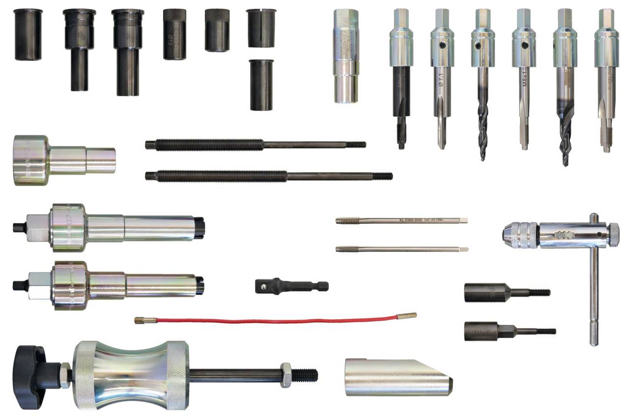 Ein Werkzeugsatz mit verschiedenen Metallautomotivartikelwerkzeugen, einschließlich Steckdosen, Bohrer, Adapter und einen Verstellschlüssel, ordentlich auf weißem Hintergrund angeordnet.