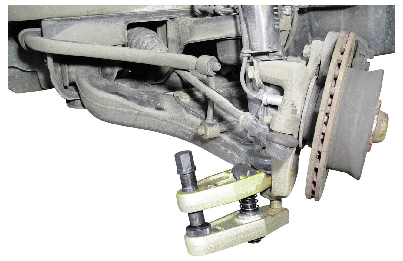 # Vorderradaufhängung und Bremsscheibenbaugruppe eines Fahrzeugs, bei der ein Kugelgelenk-Abzieher bei Wartungs- oder Reparaturarbeiten verwendet wird.