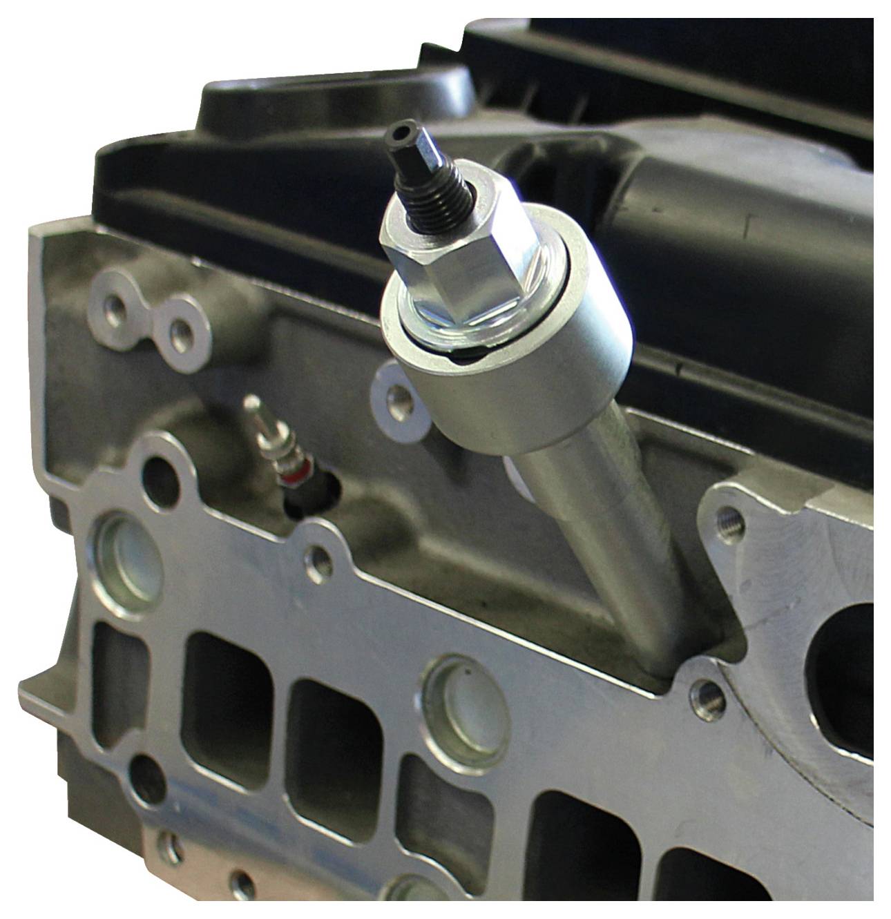 Ein Motorblock mit einem daran befestigten Kurbelwellensensor, der einen Teil der metallischen Struktur des Motors und Schraubverbindungen zeigt.