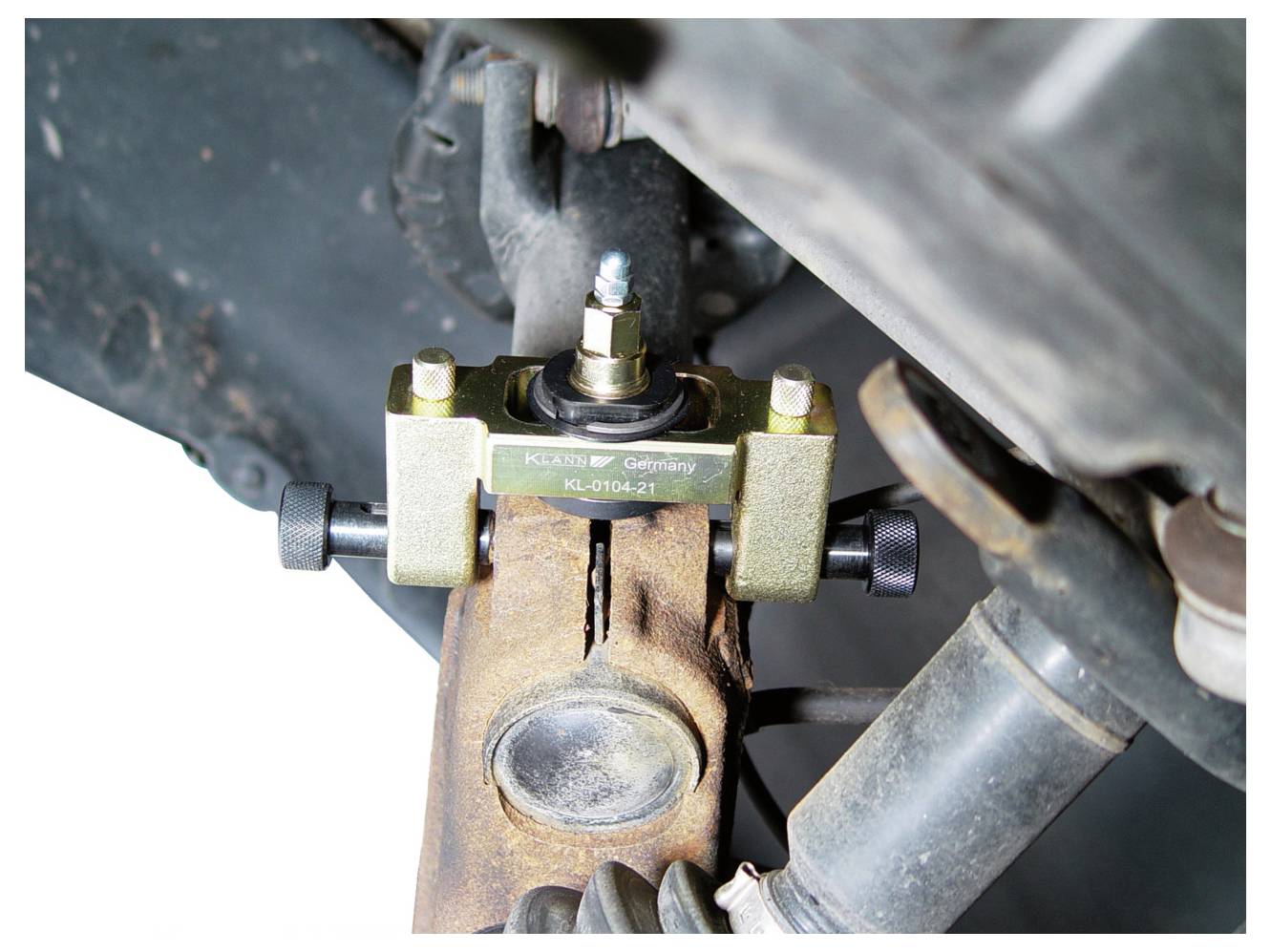 Ein U-Gelenk-Abzieher-Werkzeug entfernt ein U-Gelenk von einer Fahrzeugwelle. Das Werkzeug wird am Gelenk eingespannt zur mechanischen Extraktion.