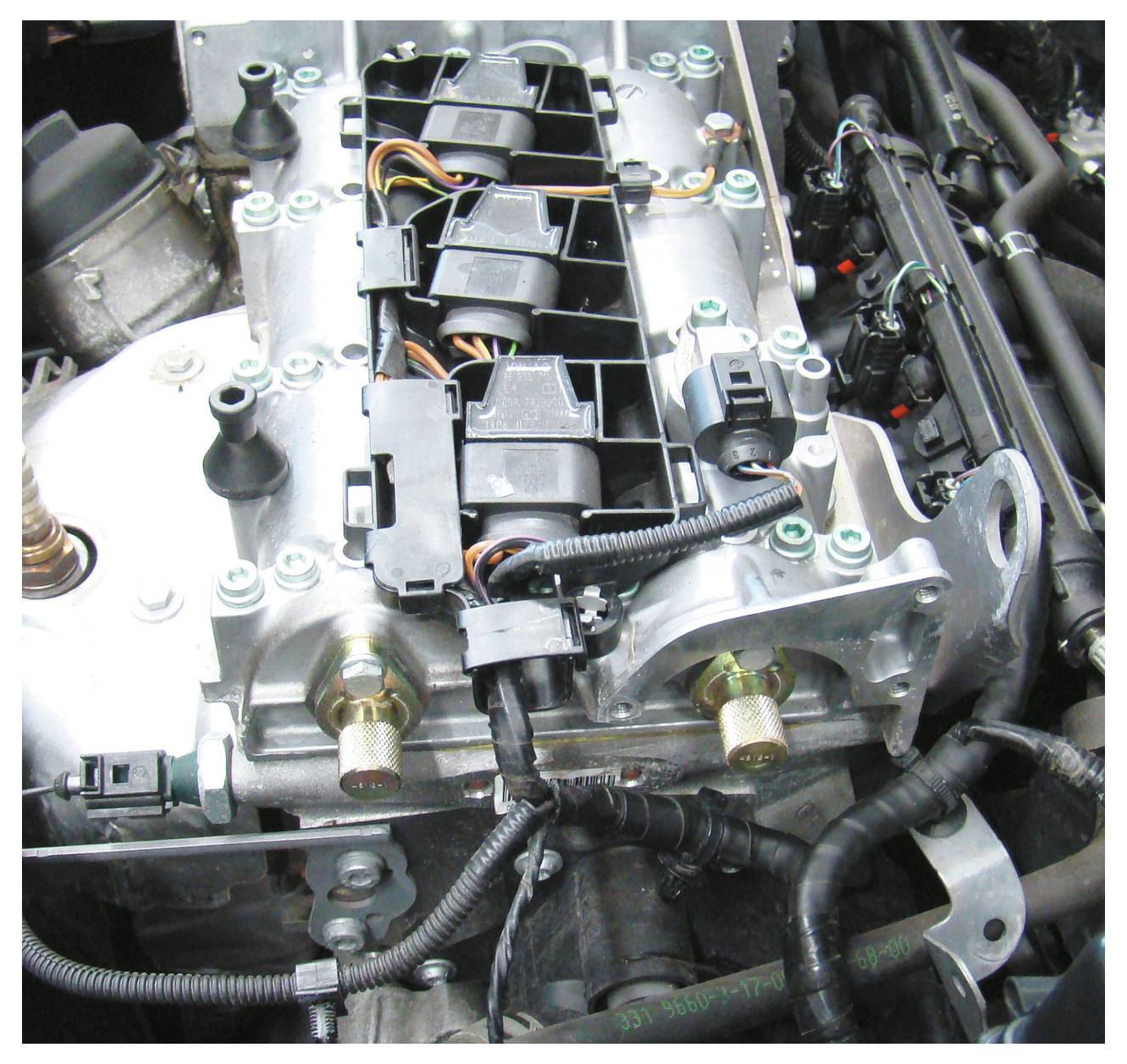 Nahaufnahme eines Automotors mit Komponenten wie Verkabelung, Kappen und Schläuchen. Fokus auf die Anordnung und Konnektivität der Teile.