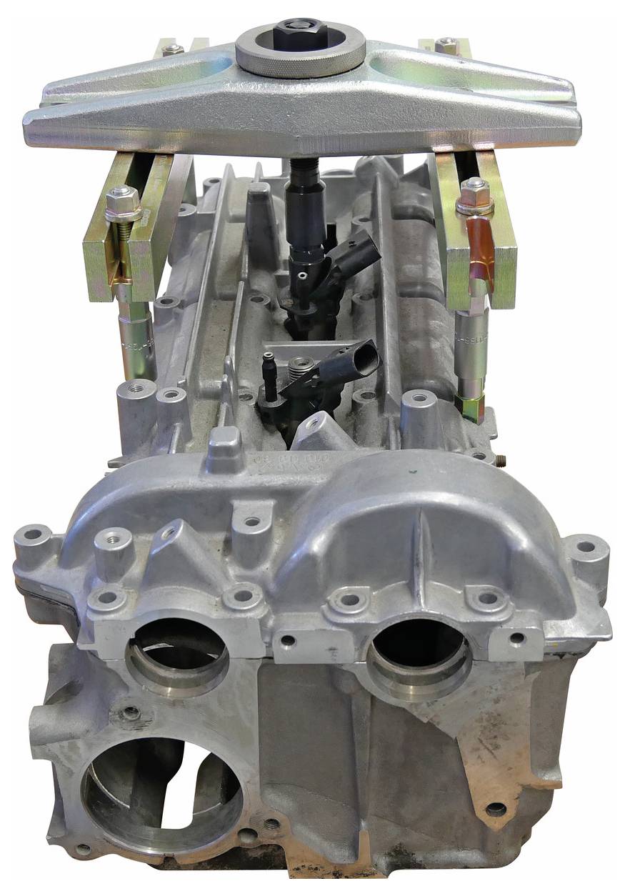 Ein Motorblock mit einem Werkzeug, das sich oben für die Ausrichtung oder Reparatur befindet, zeigt Bolzen und Verbindungspunkte.