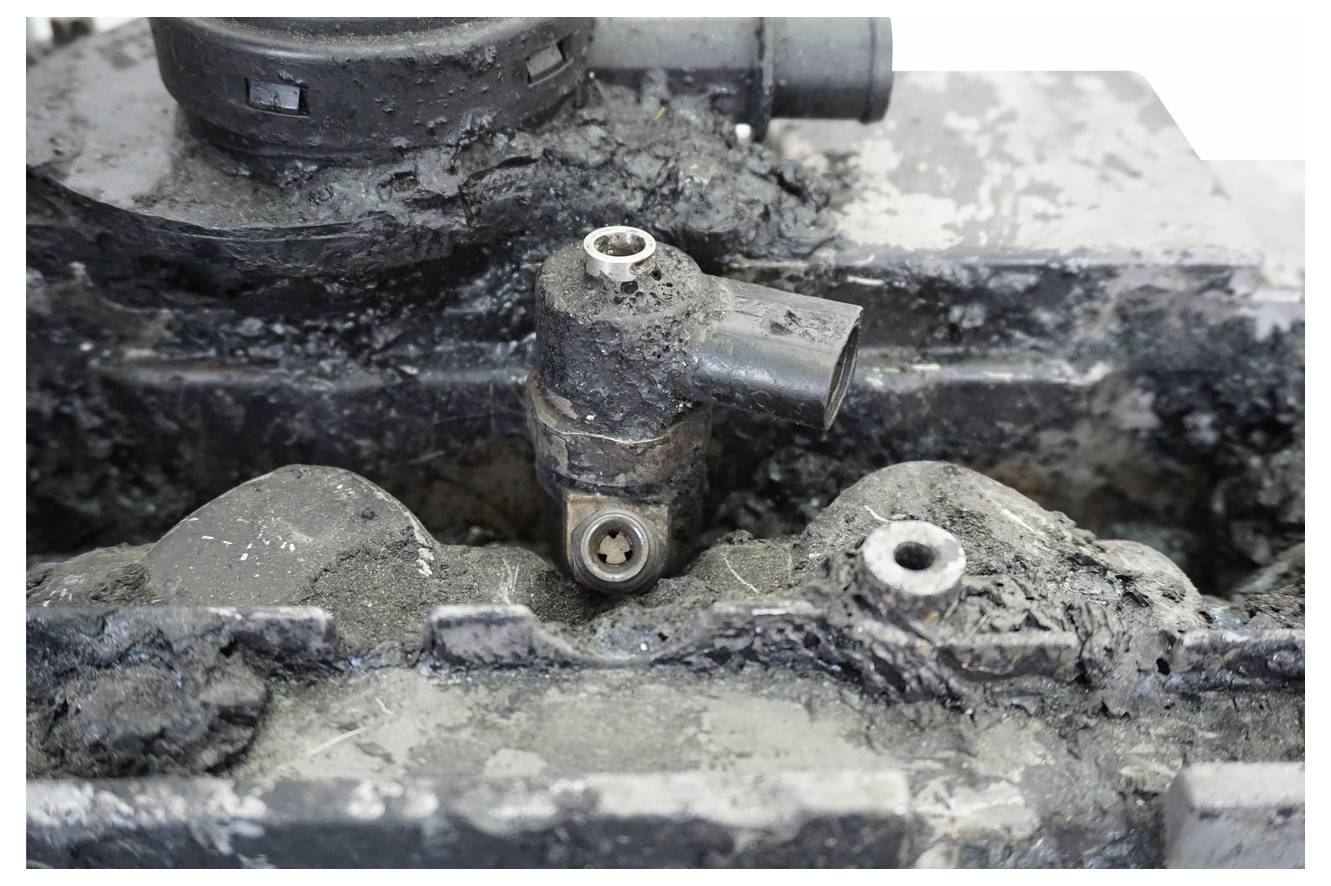 Eine Nahaufnahme eines stark verrosteten Motorenteils mit sichtbarem Rost und Schmutz, das die Verschlechterung und Beschädigung seiner Oberfläche hervorhebt.