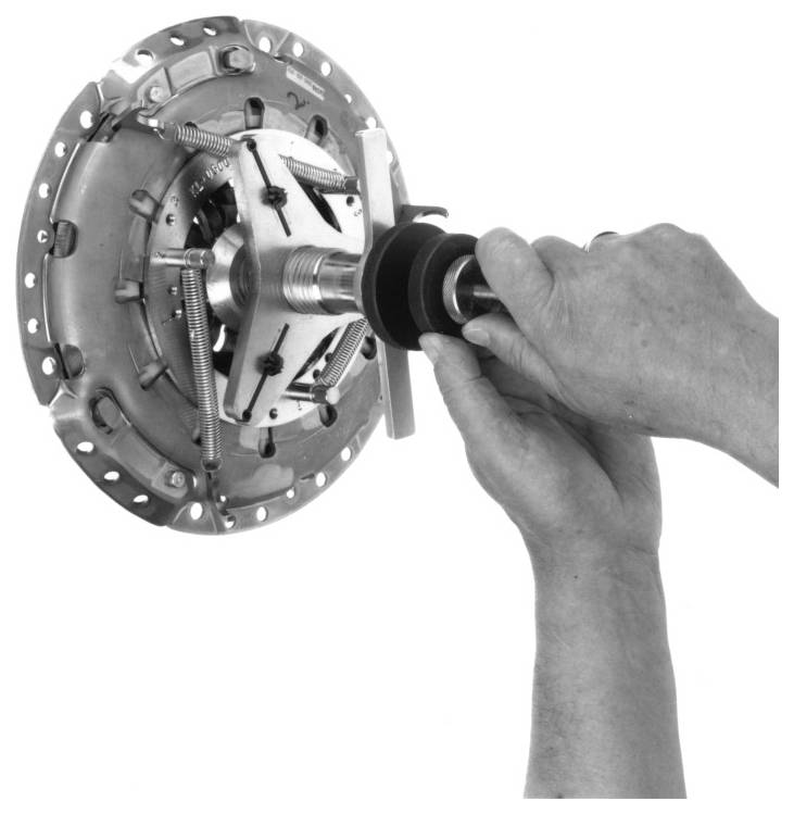 Hände halten ein Kupplungsausrichtwerkzeug und richten die Kupplungsscheibe auf der Druckplatte aus. Mechanische Anordnung, die den ordnungsgemäßen Installationsprozess demonstriert.