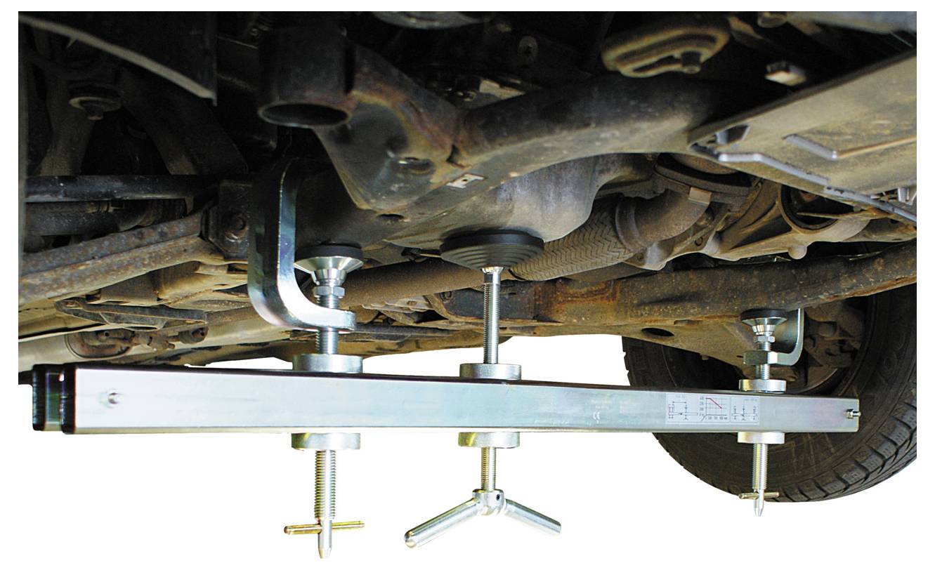 „Getriebe unter dem Fahrzeug, gesichert durch einen Tragbalken mit verstellbaren Schraubenmechanismen für Wartungs- oder Reparaturarbeiten.