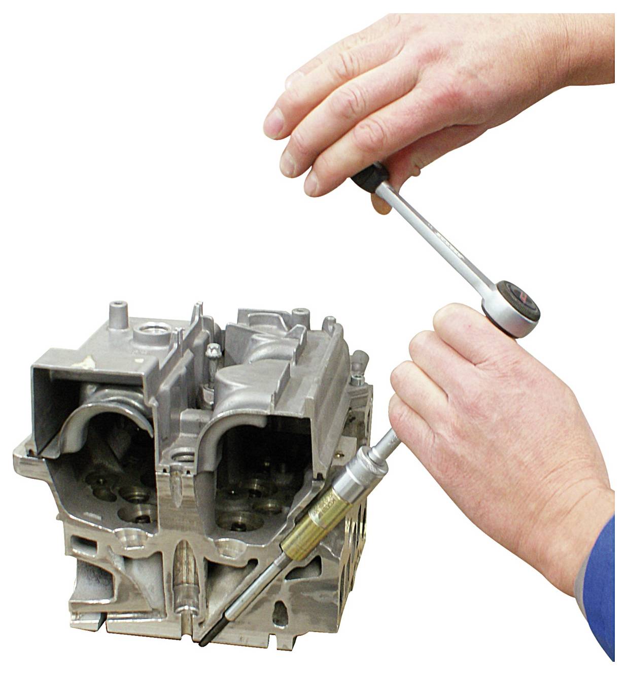 Hände verwenden einen Drehmomentschlüssel zum Anziehen einer Schraube an einem Metalleblock eines Motors und demonstrieren mechanische Reparatur oder Montage.