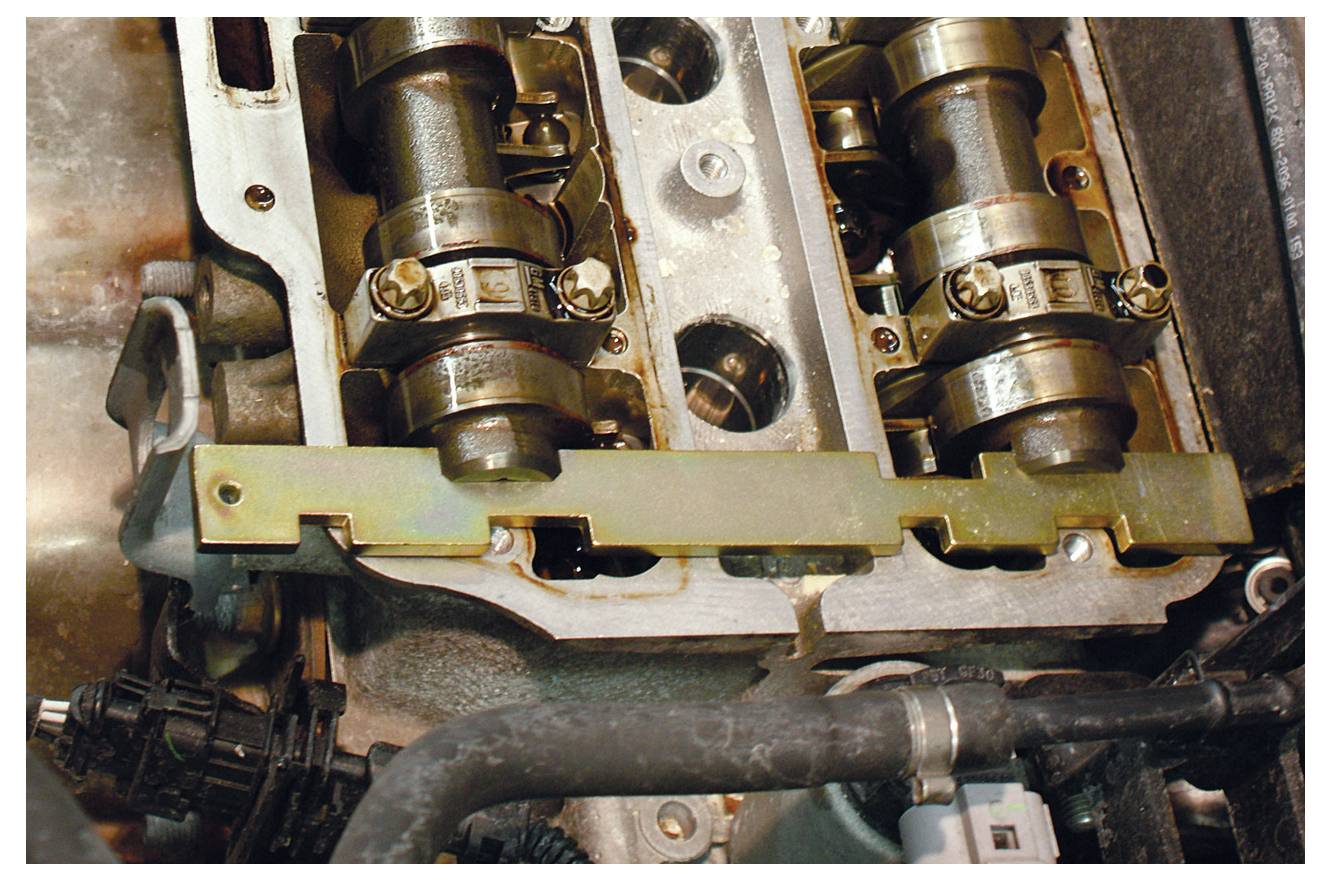 Nahaufnahme der Nockenwelle und des Ventiltriebsystems eines Automotors, mit Blick auf Metallzahnräder, Stangen und umgebende Maschinenteile.